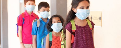School childrens standing line in front of class while maintaining social distance outside classroom with medical mask wearing - concept of covid-19 or coronavirus safety measures at school